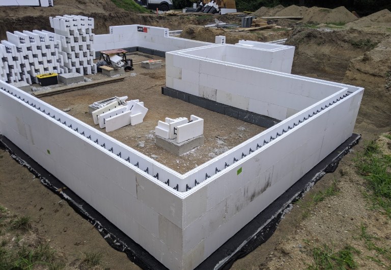 An ICF foundation stacked and squared on a Saskatchewan build site, with blocks staged ready for the next lift